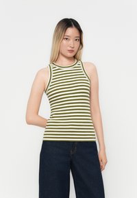 Grünes und weiß gestreiftes, geripptes Tanktop mit Rundhalsausschnitt und ärmellosem Design, kombiniert mit dunklen, weiten Jeans.