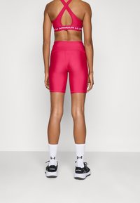 Top deportivo atlético rojo y pantalones cortos a juego de cintura alta, hechos de tela suave y elástica. Zapatillas negras para correr y calcetines blancos completan el conjunto.