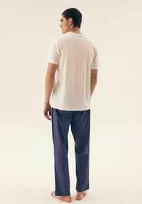 White short-sleeve t-shirt made of soft fabric, paired with navy blue loose-fitting pants, featuring a simple design and no visible patterns.