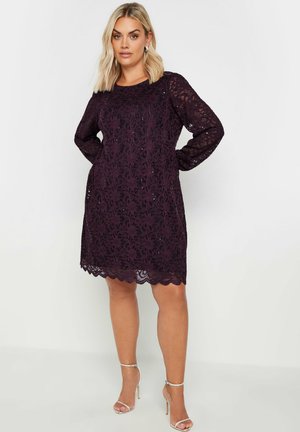 Lace dress in deep purple with long sleeves, scalloped hem, and floral pattern. Features a relaxed fit and sheer texture.