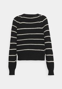 Sweter w czarno-białe paski o ryflowanej strukturze, okrągłym dekolcie, długich rękawach i krótkiej długości; dzianina wydaje się gruba.