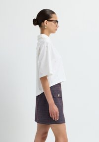 Witte shirt met korte mouwen met textuurperlenaccenten, gecombineerd met een aansluitende rok in meerdere kleuren met een zijzak en knoopdetail.