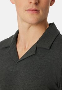 Charcoal-graues Poloshirt mit weicher Textur, ausgestattet mit einem klassischen umklappbaren Kragen und einem subtilen melierten Muster im Stoff.
