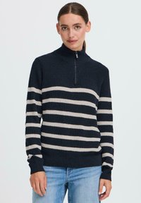 Gestreifter Pullover in Marineblau und Creme mit hohem Kragen und Viertelreißverschluss, versehen mit einem strukturierten Strickmuster sowie Rippbündchen und -saum.