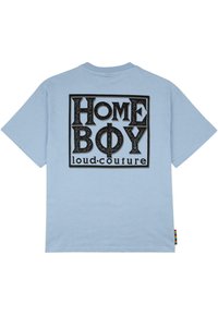 Šviesiai mėlynas medvilnės marškinėliai su ryškiu juodu grafiniu užrašu "HOME BOY loud.couture" stačiakampio rėme ant nugaros.