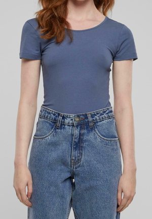 T-shirt ajusté bleu à manches courtes en coton doux, associé à un jean en denim léger taille haute avec une fermeture à bouton et des poches latérales.
