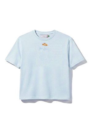 T-shirt court à manches courtes bleu clair avec un petit croissant et un texte en cursive discret sur la poitrine.