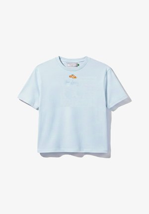 T-shirt court à manches courtes bleu clair avec un petit croissant et un texte en cursive discret sur la poitrine.