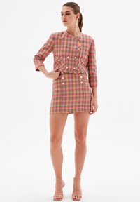 Textured pink and yellow plaid two-piece outfit with a cropped jacket featuring buttons and a mini skirt with double-button accents.