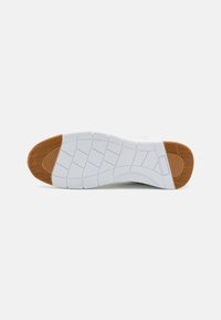 Shoe sole featuring a white rubber base with textured grooves and a brown herringbone pattern toe cap for traction and stability.