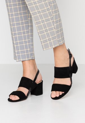 Black suede sandals featuring an open toe, two wide straps across the foot, and a block heel. Includes a slingback with a button detail.