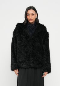Czarny płaszcz z futra ekologicznego o pluszowej teksturze, szerokim kołnierzu i długich rękawach, z otwartym przodem i luźnym fasonem.
