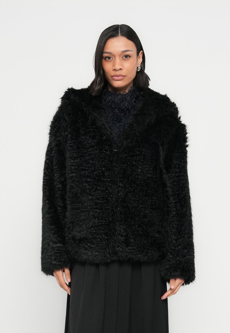 Czarny płaszcz z futra ekologicznego o pluszowej teksturze, szerokim kołnierzu i długich rękawach, z otwartym przodem i luźnym fasonem.