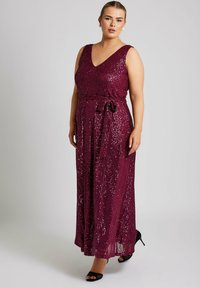 Vestido largo burdeos con lentejuelas, escote en V, sin mangas, con cintura ajustada y cinturón de lazo, que presenta una falda fluida y una abertura lateral.