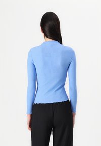 Top a maniche lunghe blu a righe con scollo scallop, vestibilità slim e tessuto testurizzato. Indossato con pantaloni neri testurizzati, in mostra la vista posteriore.