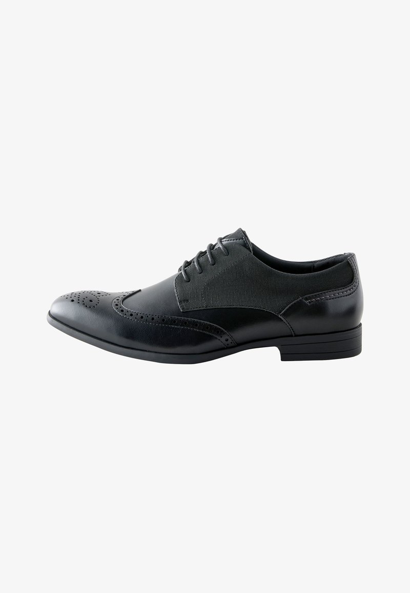 Chaussure Oxford homme en cuir noir avec détails brogue à bout ailé et panneaux en tissu, lacée, avec un talon bas et un bout pointu.