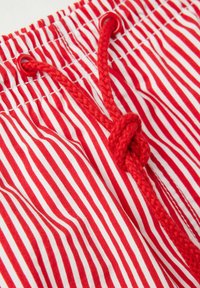 Rood-witte gestreepte shorts met een gegatherde elastische taille en een gevlochten rode koord, voorzien van plastic oogjes voor een veilige aanspanning.