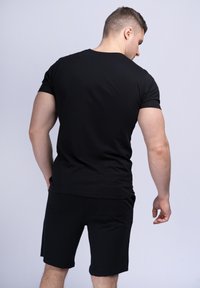 Zwarte t-shirt met korte mouwen en zwarte shorts. Gemaakt van katoen, aansluitend ontwerp, naadloze achterkant en effen, uniforme kleur zonder patronen.