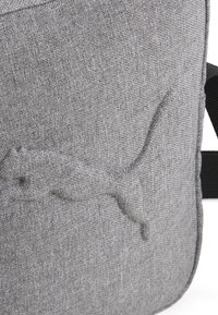Borsa in tessuto grigia con finitura testurizzata, caratterizzata da un design impresso di un animale che salta, tracolla regolabile e struttura minimalista.