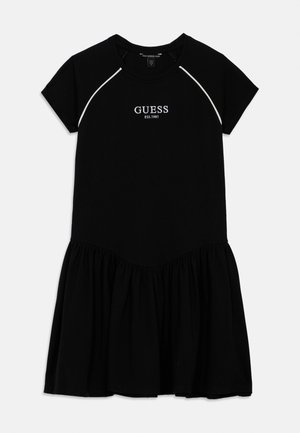 Svart bomullsklänning med korta ärmar, utställd kjol, ribbad halsringning och vit broderad "GUESS"-logotyp i övre mitten.