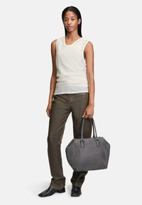 Graue Ledertasche mit strukturiertem Design, doppelten Obergriffen und Nähdetails, kombiniert mit einem hellen Tanktop und dunklen Hosen.