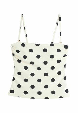 Top court blanc sans manches avec fines bretelles réglables et motif à pois noirs répartis uniformément sur le tissu.