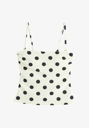 Top court blanc sans manches avec fines bretelles réglables et motif à pois noirs répartis uniformément sur le tissu.