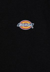 Svart bomullströja med en liten, färgglad "Dickies"-logotyp broderad på bröstet, med vita och gula accenter i en cirkulär design.