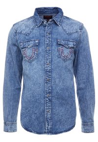 Denimskjorta i ljusblått med en urtvättad textur. Har en krage, två bröstfickor och dekorativ sömnad i röd färg. Knappstängning framtill.