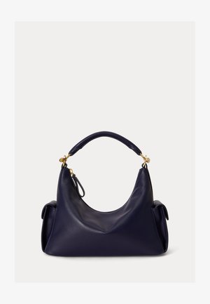 Tume sinise nahast käekott lühikese sangaga, kuldsete detailidega ja küljetaskutega, esitatud ühtlase hele tausta ees.