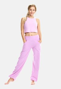 Svetloružový crop top a zodpovedajúce široké nohavice vyrobené z jemného materiálu. Nohavice majú bočné vrecká a vysoký pás.