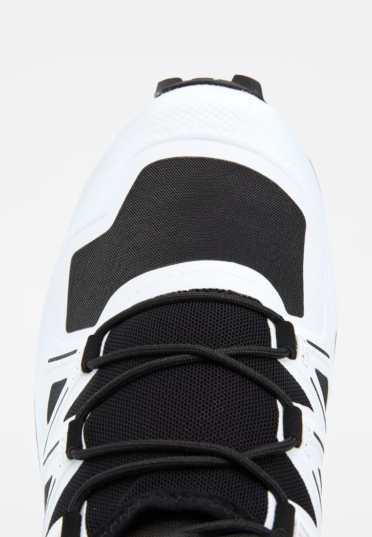 Vue de dessus d'une chaussure de sport noire et blanche en tissu mesh avec des lacets noirs sur fond blanc.