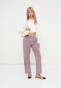 Lichtpaarse corduroy wijde broek met voorzakken en een enkele knoopsluiting, gecombineerd met een witte lange mouwen crop top en bicolor flats.