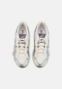 Sportiskas tenisa apavi ar krēmkrāsas sietu, sudraba akcentiem, rozā papēža detaļu un tradicionālām baltām šnūrēm. Elpojoša konstrukcija.