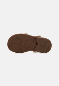 Suela de sandalia de goma marrón claro con patrones florales y de mariposas. Incluye el nombre de la marca grabado "FRIBOO" y el detalle del tamaño "25".