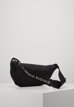 Sort bæltetaske med justerbar strop med teksten "Armani Exchange" i hvid, vist på hvidt hjørnepodie mod ensfarvet baggrund.