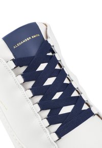 Sneaker bianca in pelle con lacci intrecciati blu navy e linguetta blu, con "ALEXANDER SMITH" in rilievo dorato.