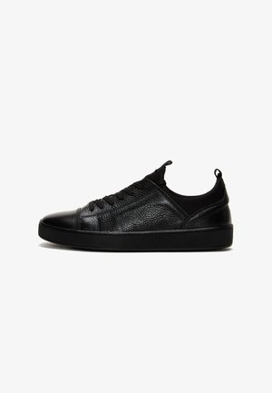 Sneaker in pelle nera con superficie testurizzata, punta rotonda, sistema di allacciatura e suola in gomma liscia con linguetta sul tallone.