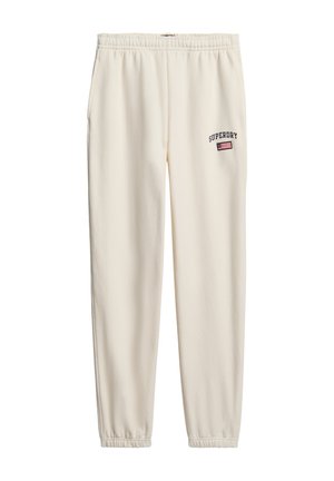 Pantalones jogger color crema con cintura elástica. Presenta el logo de "SUPERDRY" y un parche de bandera cerca de la cadera. Tejido suave, diseño de pierna tapered.