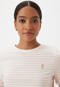 Striped short-sleeve t-shirt in soft fabric, featuring light pink and white stripes, rounded neckline, and small embroidered logo on the chest.