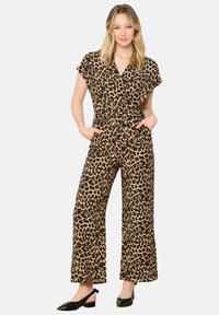 Mono de leopardo con mangas cortas, cintura ceñida, piernas anchas y bolsillos laterales. El material parece suave con una textura lisa.