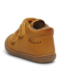 Bruine leren peuterschoen met een zachte, gestructureerde binnenkant, klittenbandsluitingen en rubberen zool, met een klein logo aan de zijkant.