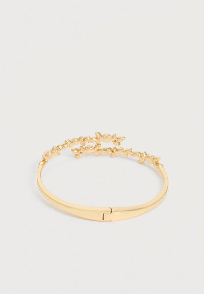 Βραχιόλι σε χρυσό χρώμα με λεπτό σχέδιο από κληματαριά και φύλλα, που διαθέτει λείο καμπυλωτό μπάντα και κούμπωμα.