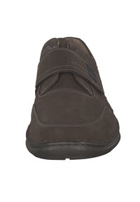 Zapato de cuero marrón con superficie texturizada, detalles de costura y una correa de velcro para un ajuste ajustable. Suela de goma plana.