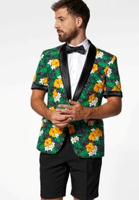 Květinový blazer v zelené, žluté a bílé barvě s černými akcenty a saténovým klopem, spárovaný s černými šortkami s tropickým designem.