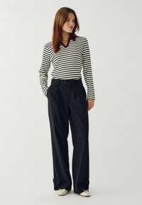 Garais piedurkņu svītrainais tops melnbaltā krāsā ar bordo apkakli, apvienots ar augsto jostasvietu melnajām biksēm ar aprocēm un pogu detaļām.