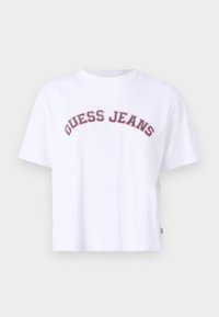 Balta medvilnės marškinėliai su apvaliu kaklu, trumpomis rankovėmis ir raudonu bei mėlynu "GUESS JEANS" logotipu, kuris išsitenka per priekį.