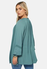 Teal, långärmad blus med samlad halsringning och veck; spetsdetaljer på ärmarna; lättviktig tyg; avslappnad passform.