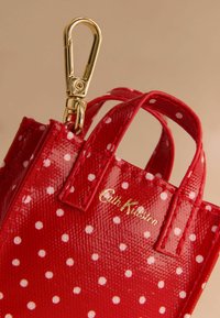 Punane täpiline kott läikiva viimistlusega, kahekordsete sangade ja kuldse metallklipiga. Küljes "Cath Kidston" logo kuldse värvusega.