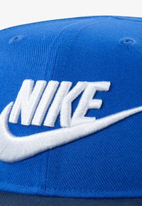 Blaues Baseballcap aus Stoff mit gesticktem weißen "Nike"-Logo und Swoosh-Design. Verfügt über eine strukturierte Form und eine strukturierte Oberfläche.